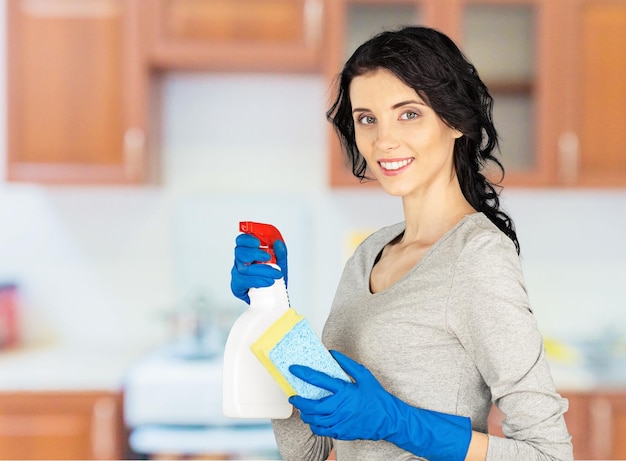 Cleaning woman with spray bottle and gloves on background