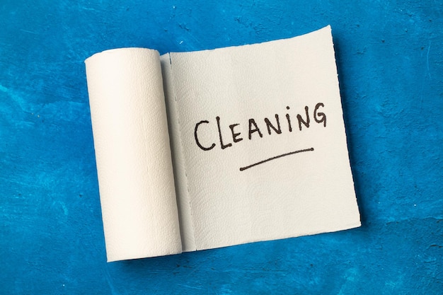 Cleaning word write on a paper kitchen napkin roll on a blue background in a top view