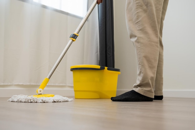 Cleaning workers mopping the wet area. There was spill water on the wooden floor in the living room.