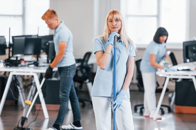 Cleans floor Group of workers clean modern office together at daytime