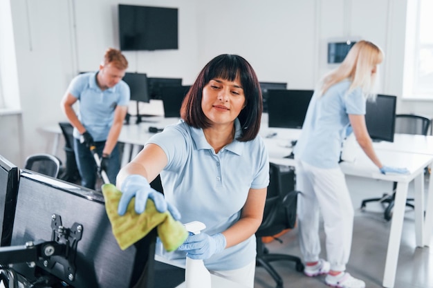 Photo cleans monitor group of workers clean modern office together at daytime