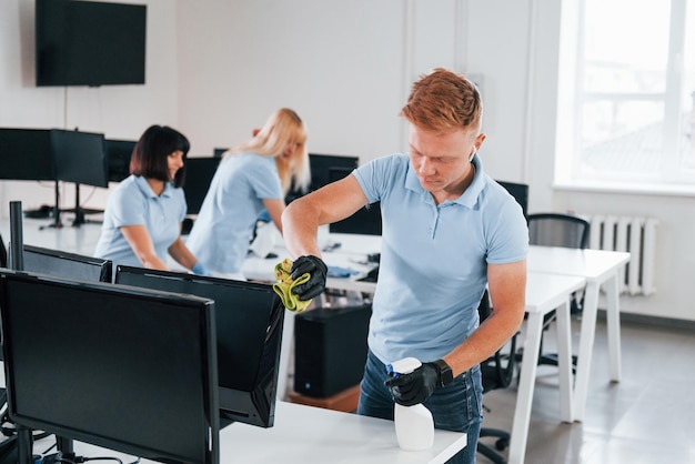 Cleans monitor Group of workers clean modern office together at daytime