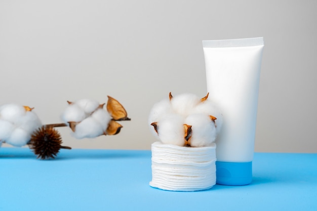 Cleansing gel and stack of cotton pads on paper background