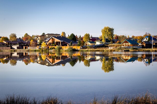 Foto chiara giornata soleggiata d'autunno ci sono case di legno sulla riva del lago foglie gialle sugli alberi