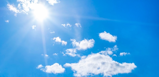 澄んだ青い空と太陽の下の明るい雲