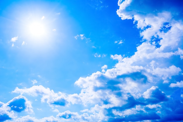 Clear blue sky with fluffy clouds and sunbeams