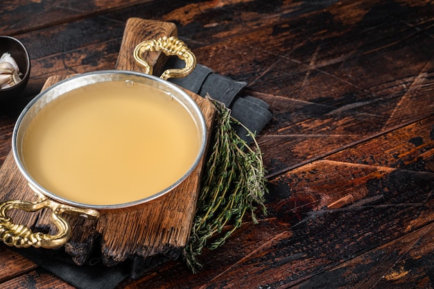 Clear broth stock without meat in cooking skillet Wooden background Top view Copy space