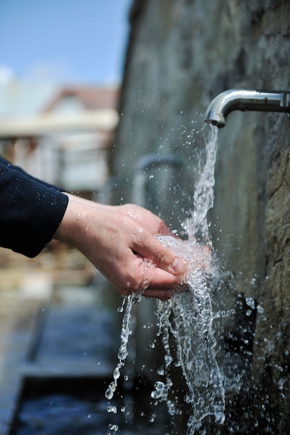 clear fresh mountain water falling on hands outdoor in nature