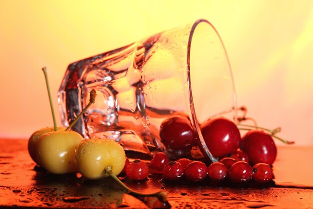 Clear glass mug with cherries on a toned background Closeup of berries with water drops