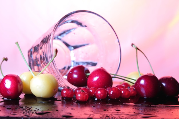 Clear glass mug with cherries on a toned background Closeup of berries with water drops