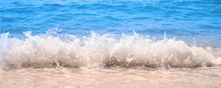 Фотография прозрачная голубая морская вода или жидкая морская волна, плещущаяся и плещущаяся до светло-коричневого песка.