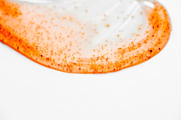 A clear plastic bottle with orange and red powder on it.