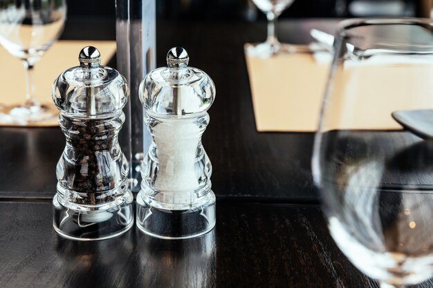 Clear plastic Pepper and Salt grinders on wooden table for food seasoning with copy space. 