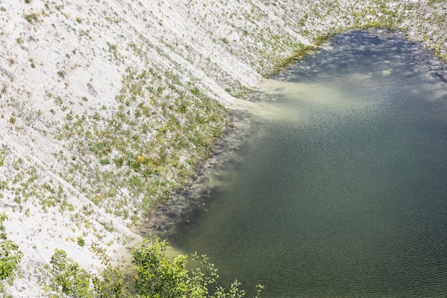 Foto acqua limpida in una cava di gesso con una ripida sponda ricoperta di erba e cespugli