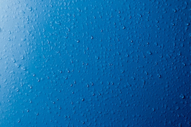 Clear water drops on a blue surface Abstract background