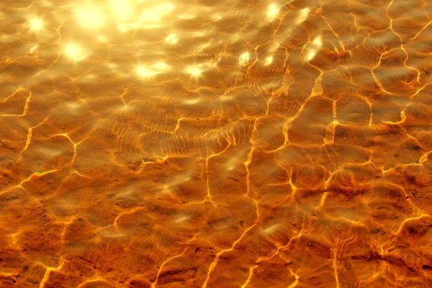 Clear water of golden color with a sandy bottomToned