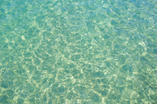 Clear water green and small waves with reflections from the sun