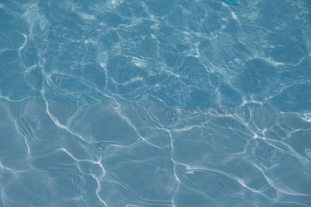 파란색 타일이 있는 수영장의 맑은 물 표면. 현대적인 미니멀리스트 건축. 물결 모양의 물.