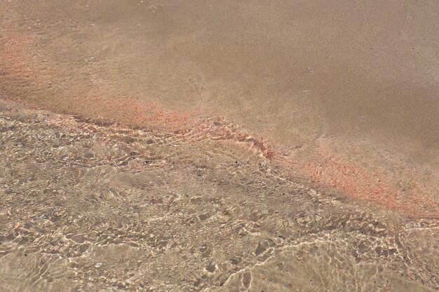 Clear waves and colorful sand on tropical sandy beach in Crete Greece.