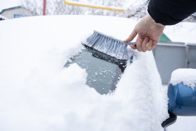 車のブラシで車のフロントガラスから雪を取り除く