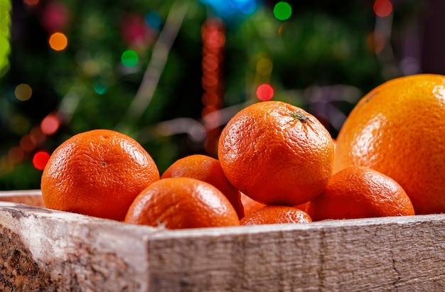 Clementines or tangerines in the box on christmas lights.