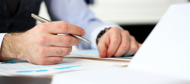 Clerk man at office workplace with silver pen in arms