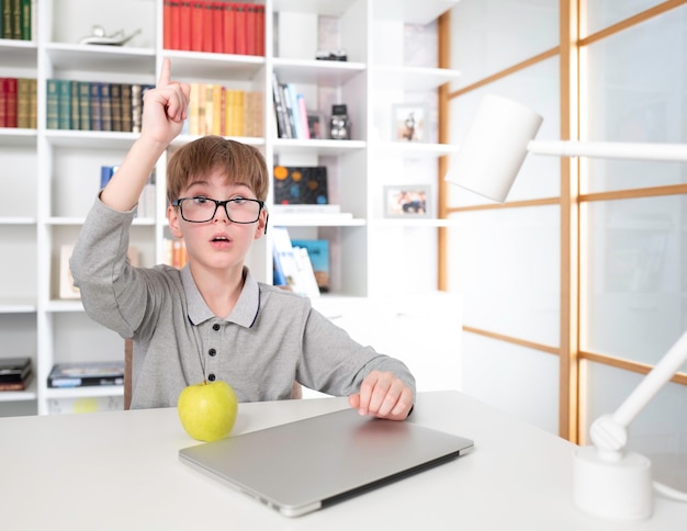 Clever child sitting on the desk against the background of bookshelf