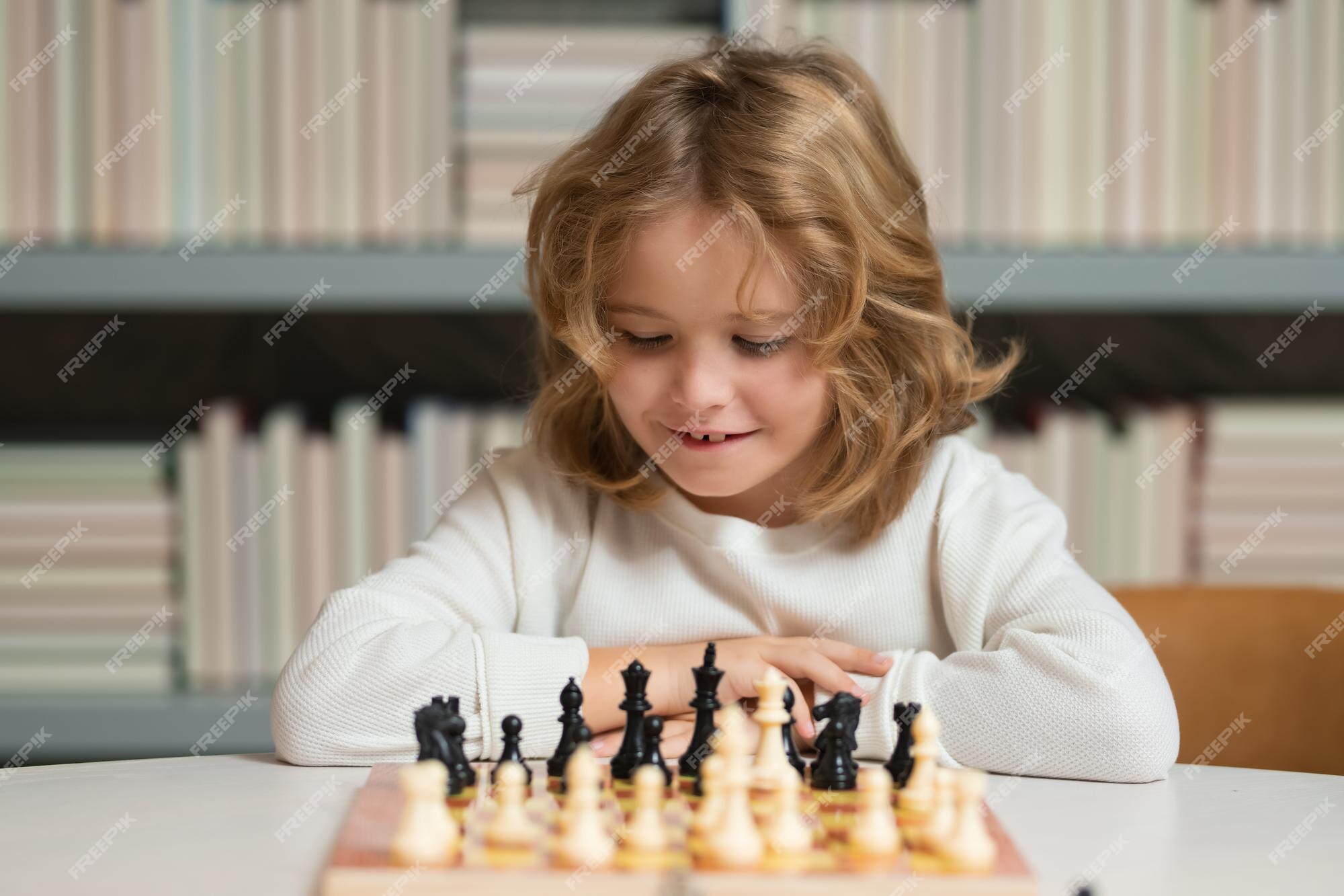 Pupil kid thinking about his next move in a game of chess. Concentrated  little boy sitting at the table and playing chess Stock Photo - Alamy