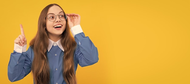 Clever idea Clever girl in eyeglasses yellow background School age child with raised finger Eureka Child face horizontal poster teenager girl isolated portrait banner with copy space