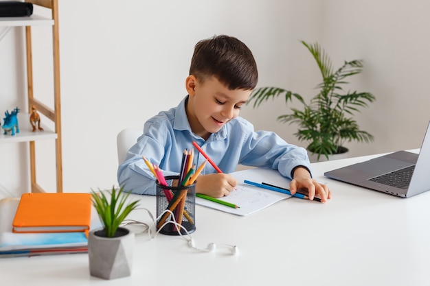 Ragazzo intelligente che fa i compiti utilizzando laptop e internet