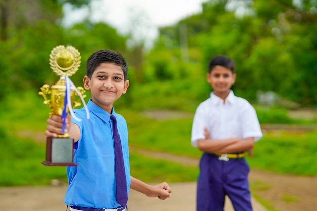 Clever schoolboy raising his trophy as a winner in school competition and celebrate with his friend.