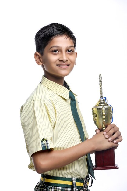 Clever schoolboy raising his trophy as a winner in school competition.