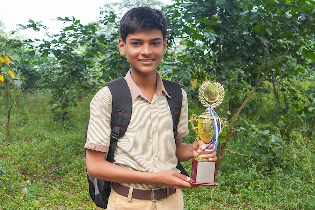 Clever schoolboy raising his trophy as a winner in school competition