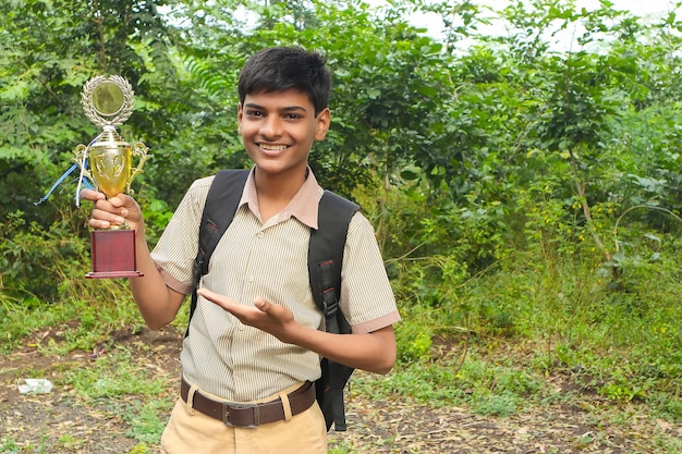 学校の大会で優勝者としてトロフィーを掲げる賢い男子生徒
