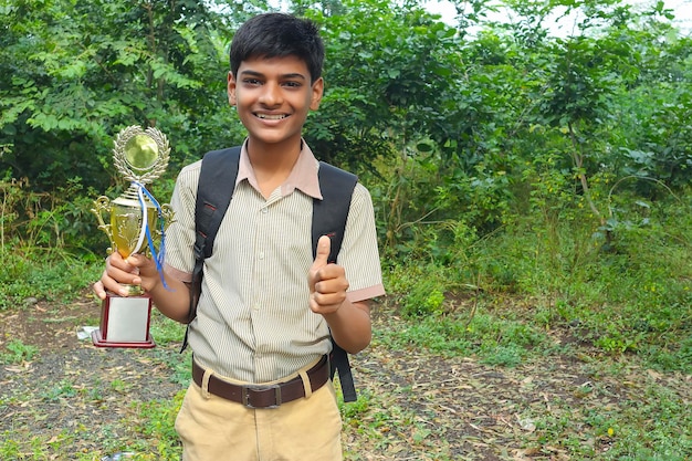 Clever schoolboy raising his trophy as a winner in school competition