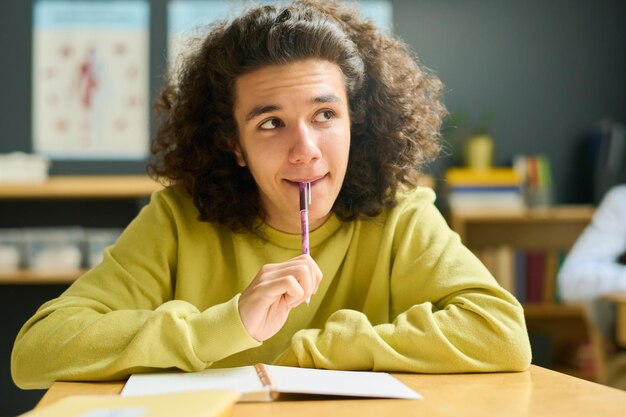 Adolescente intelligente in abbigliamento casual che guarda l'insegnante o la lavagna a lezione