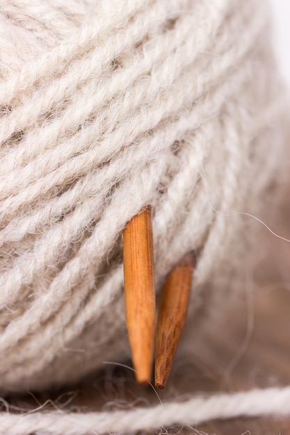 Clew wool yarn and wooden knitting needles on wooden background