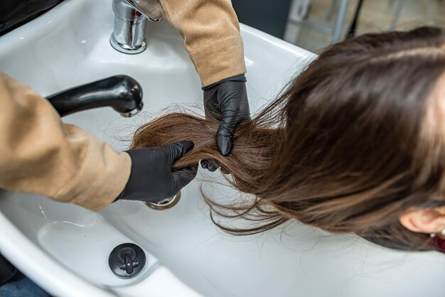 Клиент пришел в парикмахерскую, и мастер готовит волосы к мытью во время