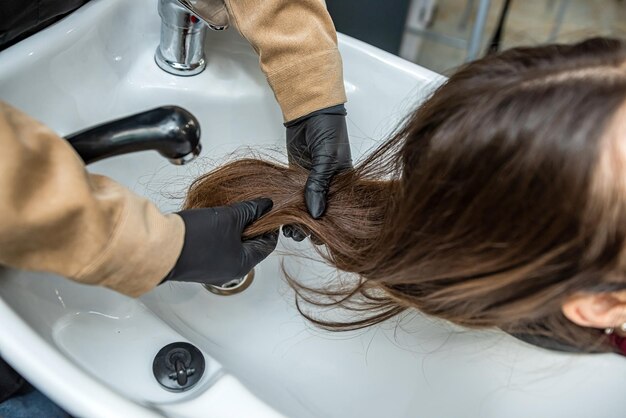 Client came to the barber shop and the master prepares the hair for washing during