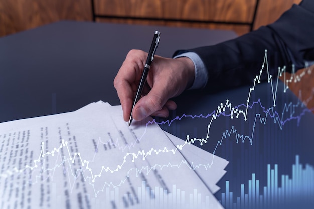 A client in formal wear is signing the contract to invest money in stock market Internet trading and wealth management concept Forex and financial hologram chart over the desk