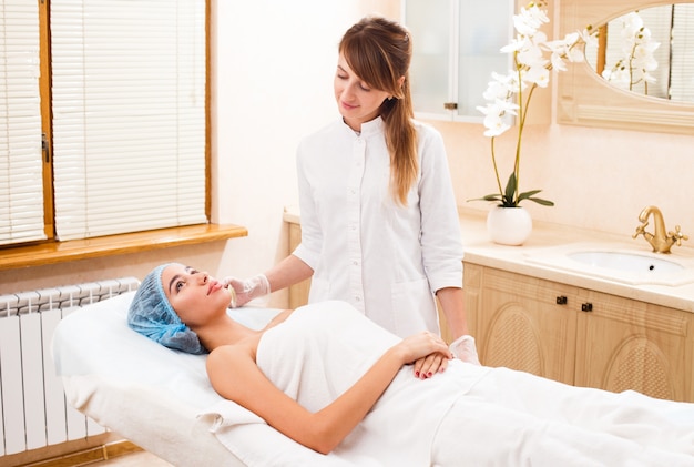 The client lies on the couch at a reception with a cosmetologist