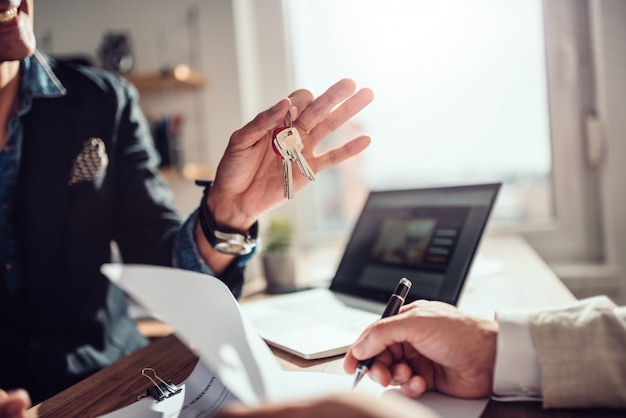 Photo client signing contract while real estate agent holding keys