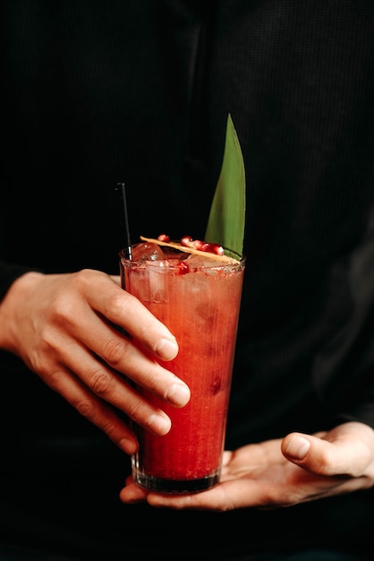 Foto un cliente si trova vicino al bancone di un bar in un caffè con un cocktail in mano