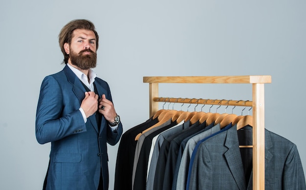 Client at the studio tailor in his workshop Handsome bearded fashion man in classical costume suit Man in custom tailored suit presenting tailored tuxedo Man clothing in boutique Man with suit