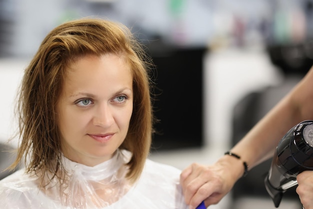 Photo client woman after refreshing haircut looking in mirror on herself