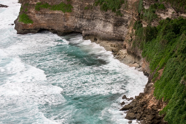 Scogliere sopra il mare tropicale blu con paesaggio verde. nusa dua. uluwatu bali indonesia