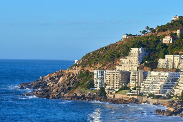 澄んだ青い空のホテルとアパートの建物を背景にしたクリフトンケープタウン南アフリカのパノラマ海景美しい青い海半島を見下ろす住宅開発