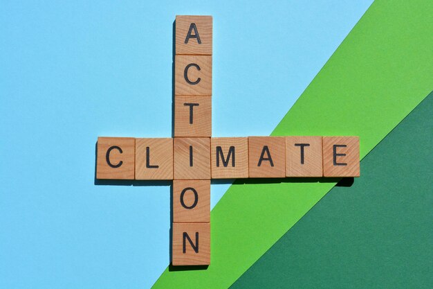 Foto parole di azione climatica in lettere dell'alfabeto in legno in forma di incroci isolate su sfondo blu-verde