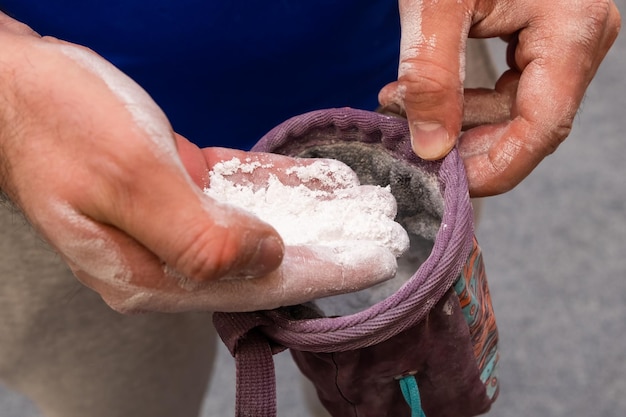 Scalatore che applica polvere di gesso per l'arrampicata su roccia nella palestra di bouldering