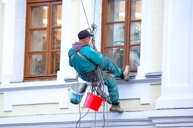 Climber bedient het raam en de gevel van een woongebouw in reparatiebouw